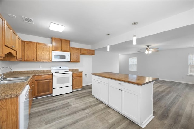 kitchen featuring sink, white appliances, decorative light fixtures, and light hardwood / wood-style floors