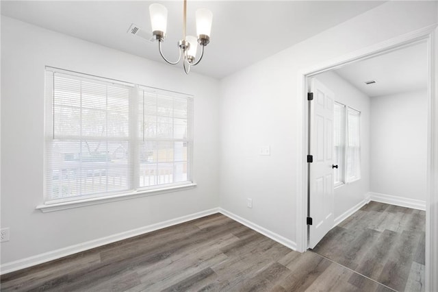 empty room featuring a notable chandelier and dark hardwood / wood-style flooring