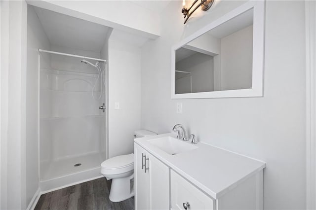 bathroom featuring vanity, hardwood / wood-style flooring, walk in shower, and toilet