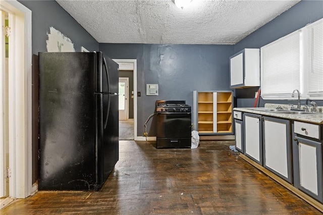 kitchen featuring white cabinets, dark wood-type flooring, a textured ceiling, black appliances, and a sink