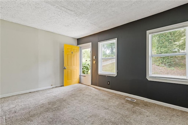 empty room featuring carpet floors, plenty of natural light, visible vents, and baseboards