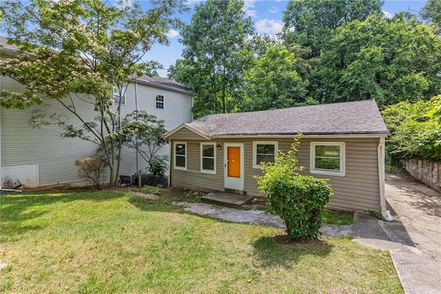 view of front of home featuring roof with shingles and a front lawn