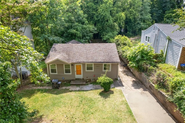 view of front facade with a shingled roof, fence, and a front yard