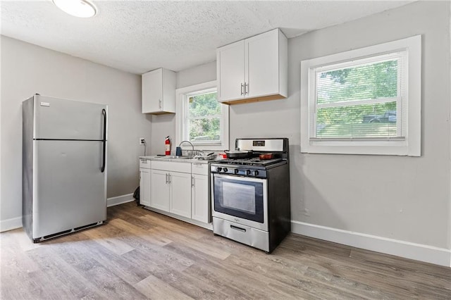 kitchen with white cabinets, light wood finished floors, and stainless steel appliances