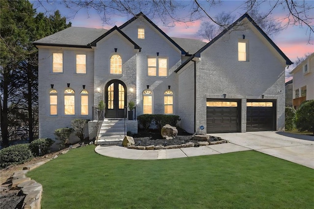 french country inspired facade with driveway, french doors, a front lawn, and brick siding