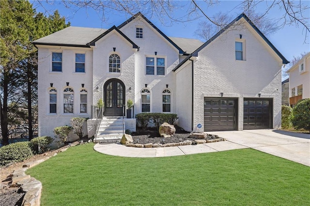 french country inspired facade featuring an attached garage, brick siding, concrete driveway, french doors, and a front lawn