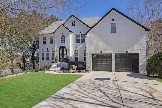 french country inspired facade with a front yard, concrete driveway, brick siding, and an attached garage