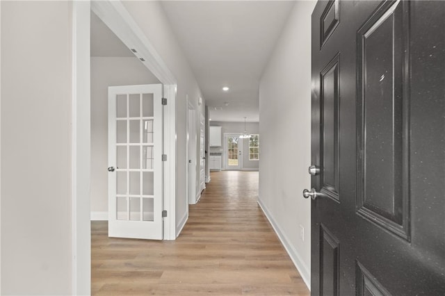 corridor featuring light wood-style flooring and baseboards