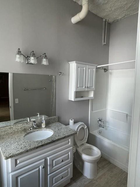 full bathroom with vanity, wood-type flooring, toilet, and washtub / shower combination