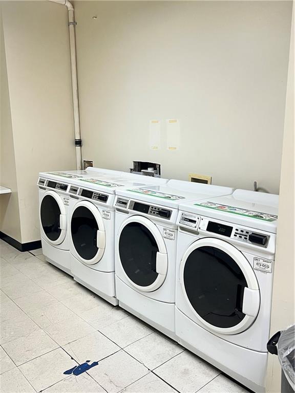 clothes washing area with independent washer and dryer and light tile patterned flooring