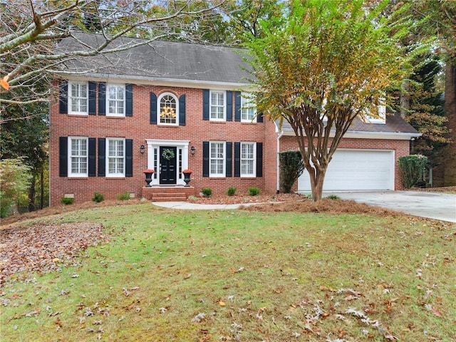 colonial inspired home featuring a garage, driveway, brick siding, and a front yard