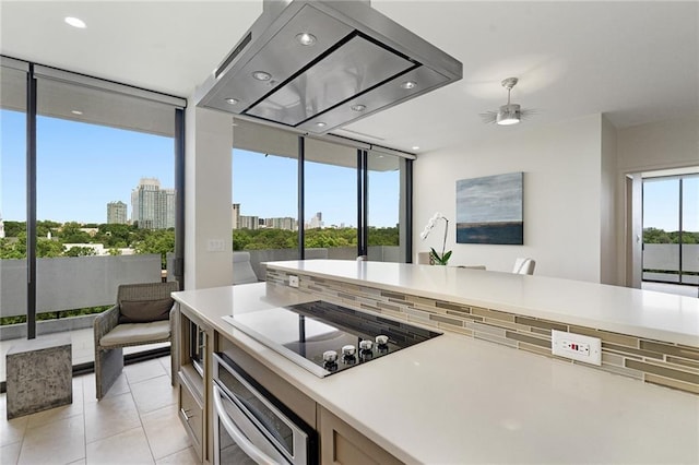 kitchen featuring floor to ceiling windows, oven, ceiling fan, light tile patterned floors, and black electric stovetop