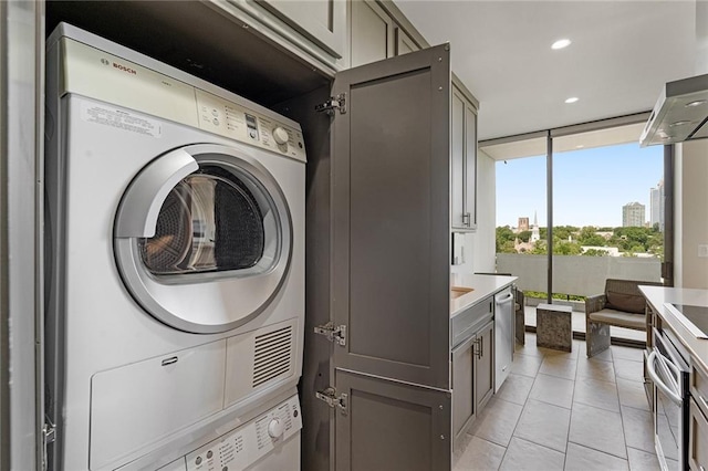 clothes washing area featuring stacked washer and dryer and light tile patterned flooring