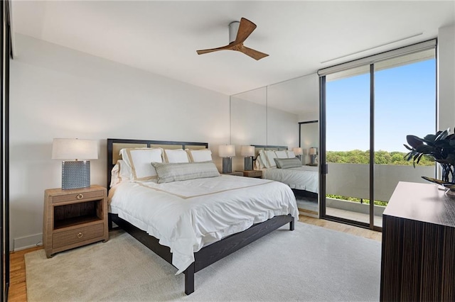 bedroom featuring light wood-type flooring, expansive windows, access to exterior, and ceiling fan