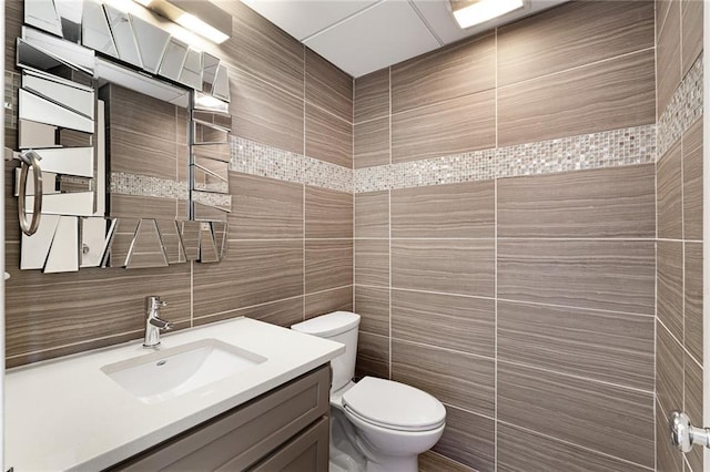 bathroom featuring tile walls, vanity, and toilet