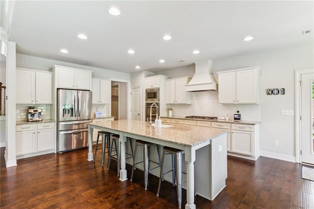 4972 Park Vale Dr, Sugar Hill, GA 30518 - kitchen featuring appliances with stainless steel finishes, premium range hood, a breakfast bar, backsplash, and a center island with sink