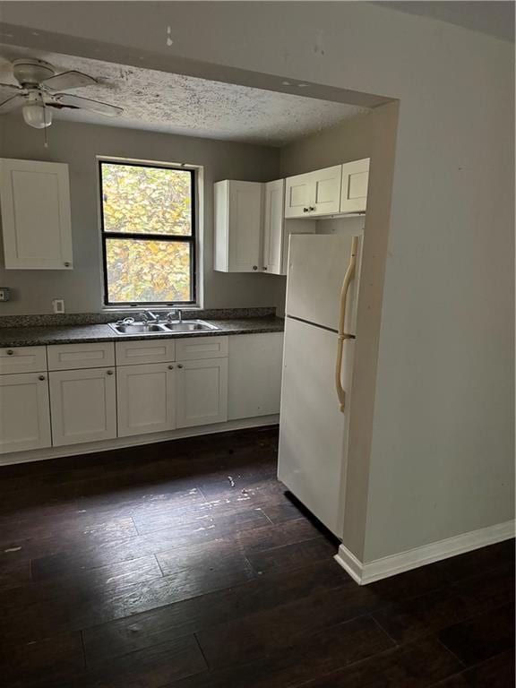 kitchen with sink, white cabinetry, ceiling fan, white fridge, and dark wood-type flooring