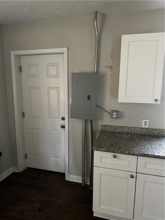 kitchen featuring electric panel, white cabinetry, dark hardwood / wood-style floors, and a textured ceiling