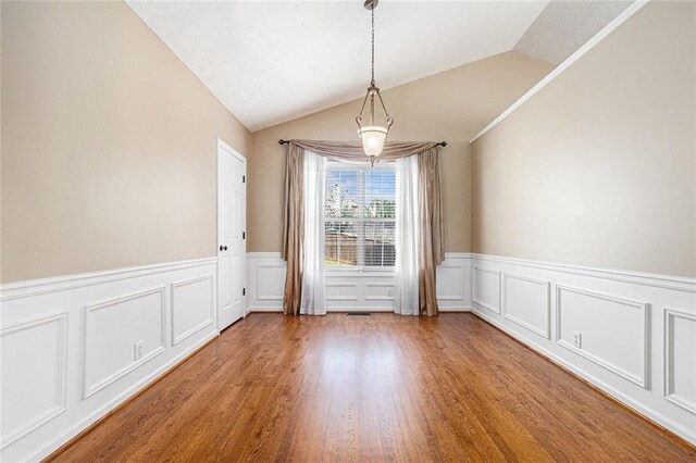 6411 Compass Dr, Flowery Branch, GA 30542 - unfurnished dining area with vaulted ceiling, a wainscoted wall, wood finished floors, and a decorative wall
