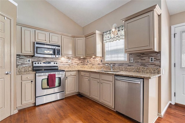 6411 Compass Dr, Flowery Branch, GA 30542 - kitchen with stainless steel appliances, cream cabinets, vaulted ceiling, backsplash, and dark wood-style floors