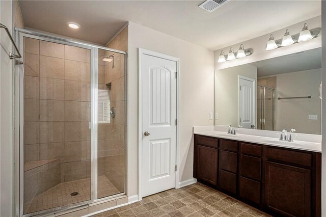 bathroom with double vanity, a shower stall, visible vents, and a sink