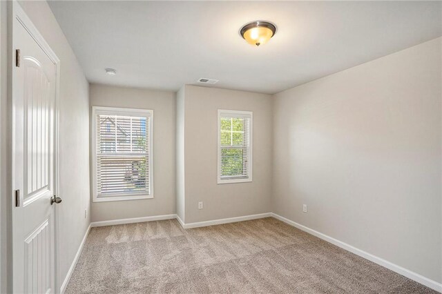 unfurnished room with light carpet, visible vents, and baseboards