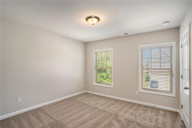 unfurnished room featuring carpet, visible vents, and baseboards