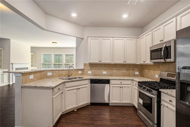 kitchen featuring light stone counters, appliances with stainless steel finishes, a sink, and white cabinetry