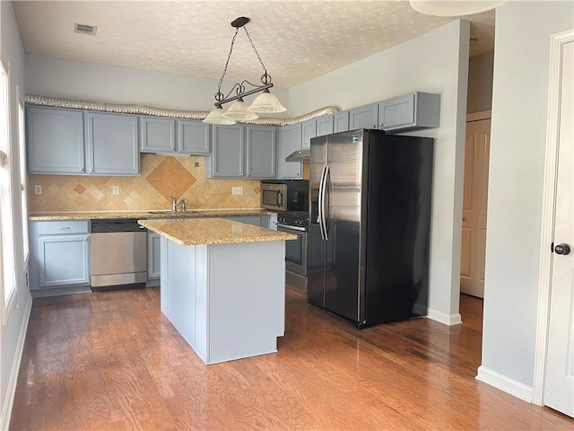 795 Abbotts Mill Ct Unit 73, Johns Creek, GA 30097 - kitchen featuring appliances with stainless steel finishes, dark wood-style floors, decorative backsplash, gray cabinetry, and a center island