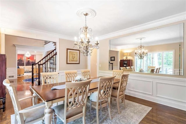 dining area with dark hardwood / wood-style floors, crown molding, and an inviting chandelier