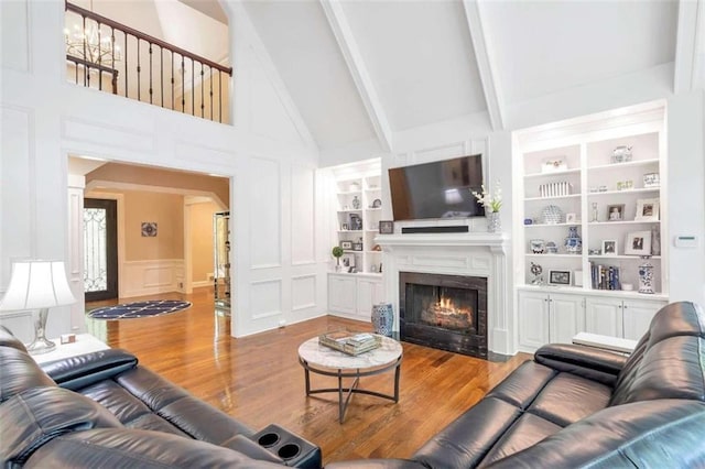 living room with built in features, a fireplace, beam ceiling, high vaulted ceiling, and wood-type flooring