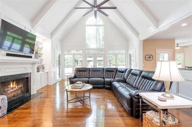 living room featuring beam ceiling, wood-type flooring, ceiling fan, and plenty of natural light