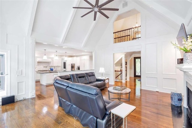 living room featuring beamed ceiling, high vaulted ceiling, ceiling fan, and hardwood / wood-style floors