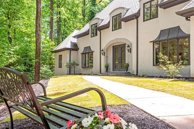 exterior space with french doors and a lawn