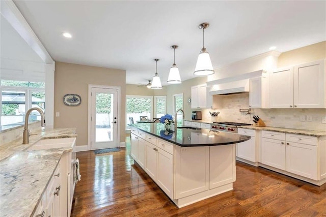 kitchen with decorative light fixtures, dark hardwood / wood-style flooring, sink, and an island with sink