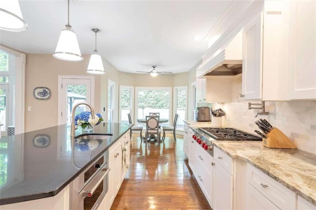 kitchen with white cabinets, backsplash, wood-type flooring, and stainless steel appliances