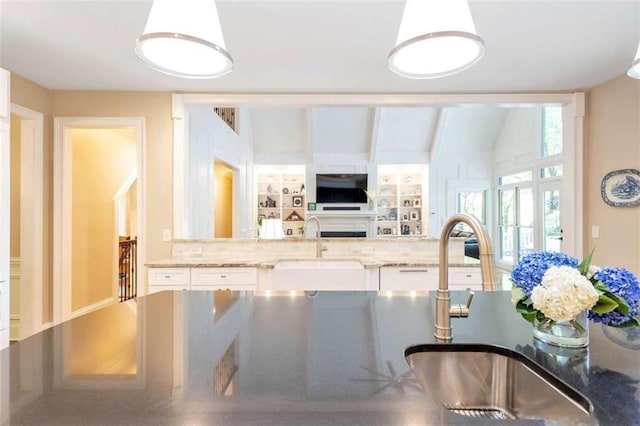 kitchen with sink, stone countertops, white cabinets, and vaulted ceiling with beams