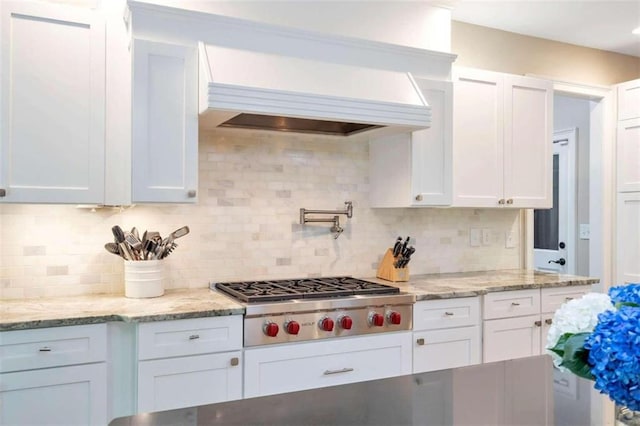 kitchen with white cabinets, decorative backsplash, stainless steel gas stovetop, and custom range hood