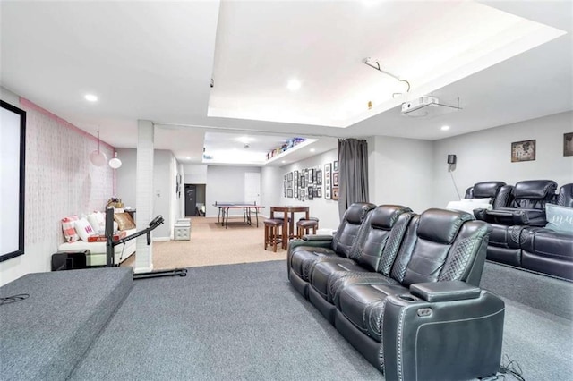 home theater room featuring a raised ceiling and carpet flooring