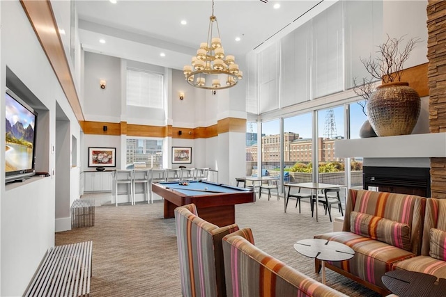 playroom featuring a towering ceiling, a stone fireplace, billiards, and light colored carpet