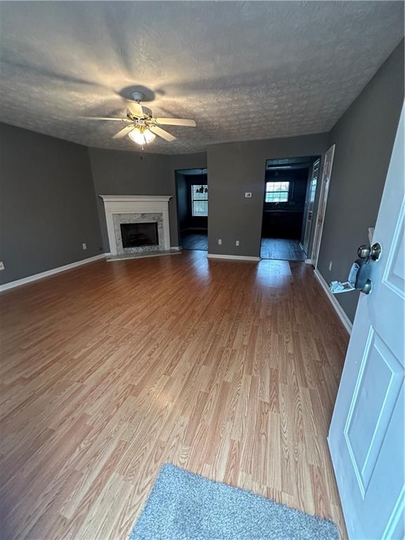 unfurnished living room featuring hardwood / wood-style flooring, ceiling fan, a textured ceiling, and a fireplace