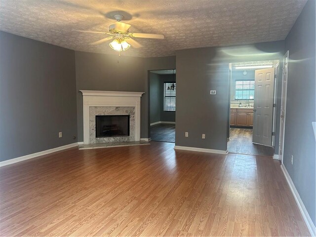 unfurnished living room with a fireplace, light hardwood / wood-style flooring, sink, and a textured ceiling