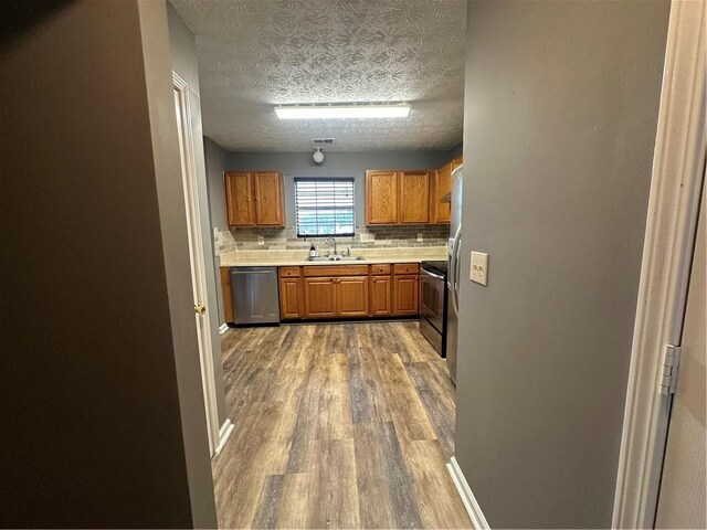 kitchen featuring sink, backsplash, stainless steel appliances, dark hardwood / wood-style floors, and a textured ceiling