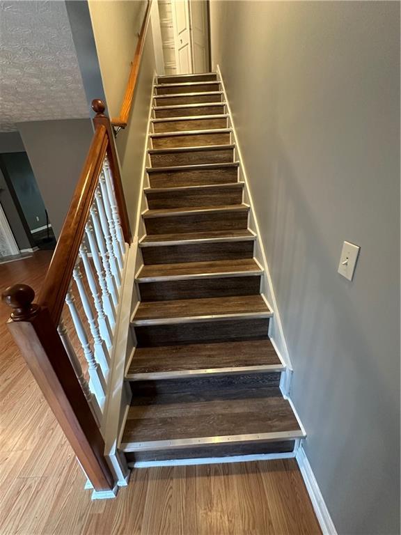 stairway featuring hardwood / wood-style flooring and a textured ceiling