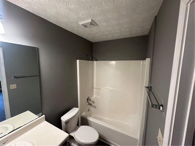 full bathroom with vanity, a textured ceiling, washtub / shower combination, and toilet