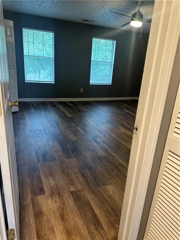 spare room with plenty of natural light, dark wood-type flooring, and a textured ceiling