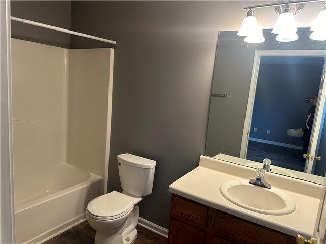 full bathroom with  shower combination, toilet, hardwood / wood-style floors, and vanity