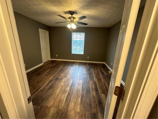 unfurnished room with ceiling fan, dark hardwood / wood-style floors, and a textured ceiling