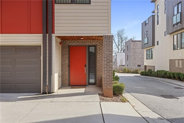 view of exterior entry with a garage and brick siding