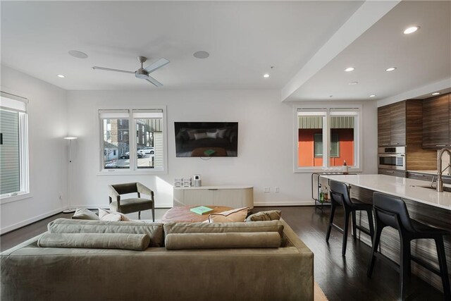 living room featuring sink, dark wood-type flooring, and ceiling fan